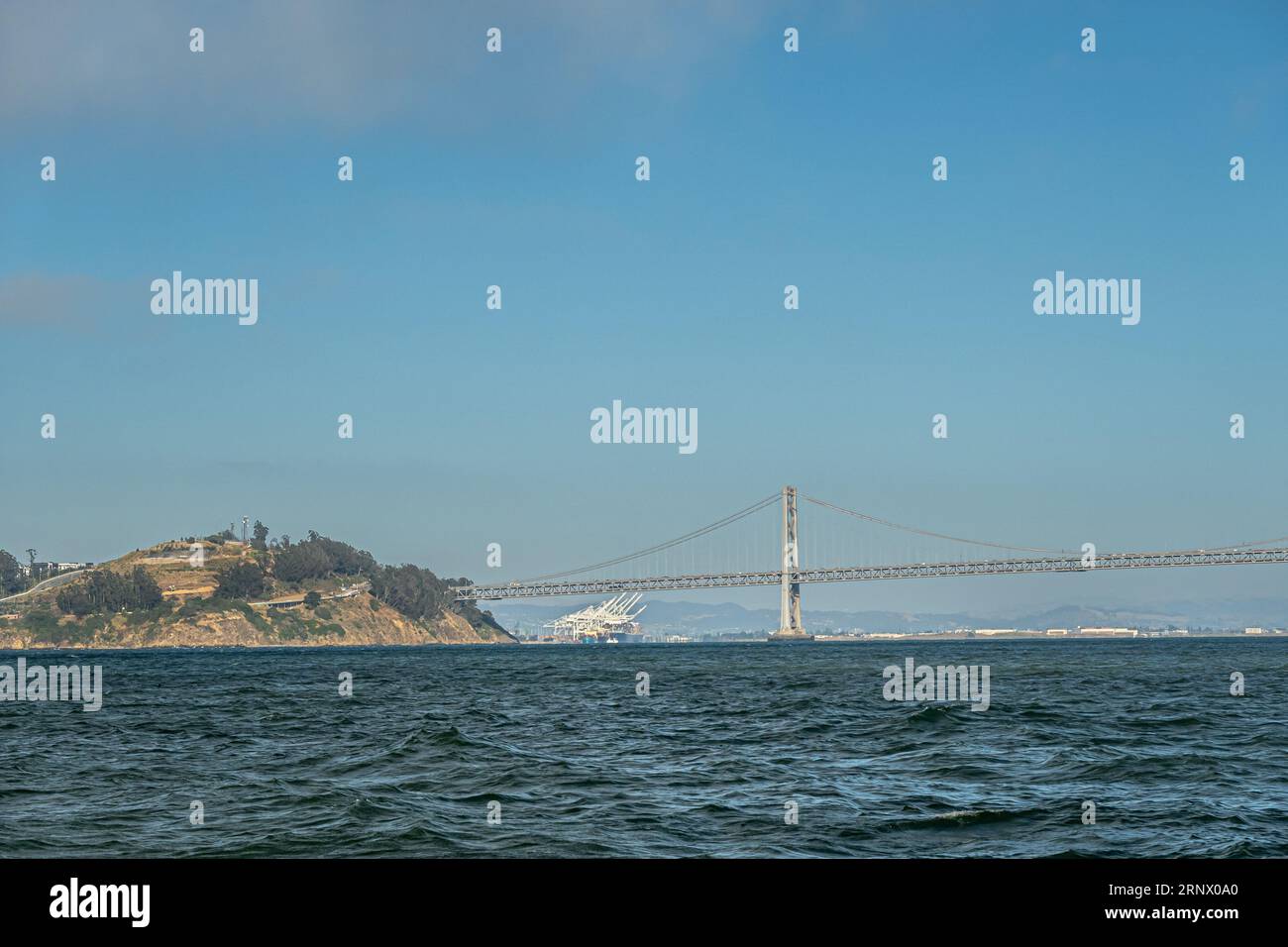 San Francisco, CA, USA - 12 juillet 2023 : Yerba Buena Island et pont suspendu SF-Oakland avec Oakland Outer Container Harbour à l'horizon. Ciel bleu A. Banque D'Images