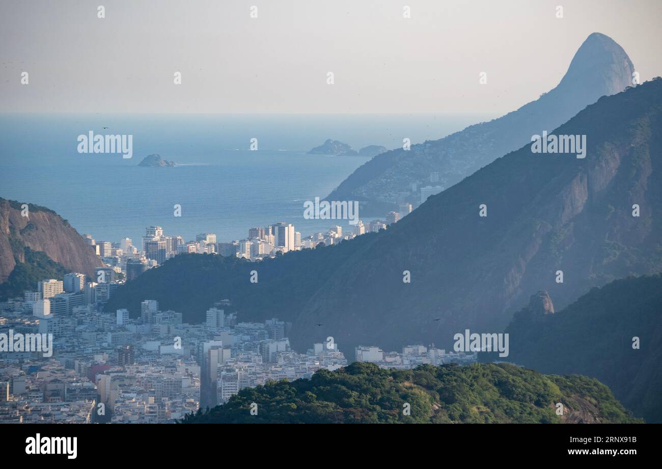 Rio de Janeiro, Brésil : vue au coucher du soleil depuis la montagne du pain de sucre (Pao de Acucar) avec vue sur les toits de la ville et les montagnes avec la forêt tropicale atlantique Banque D'Images