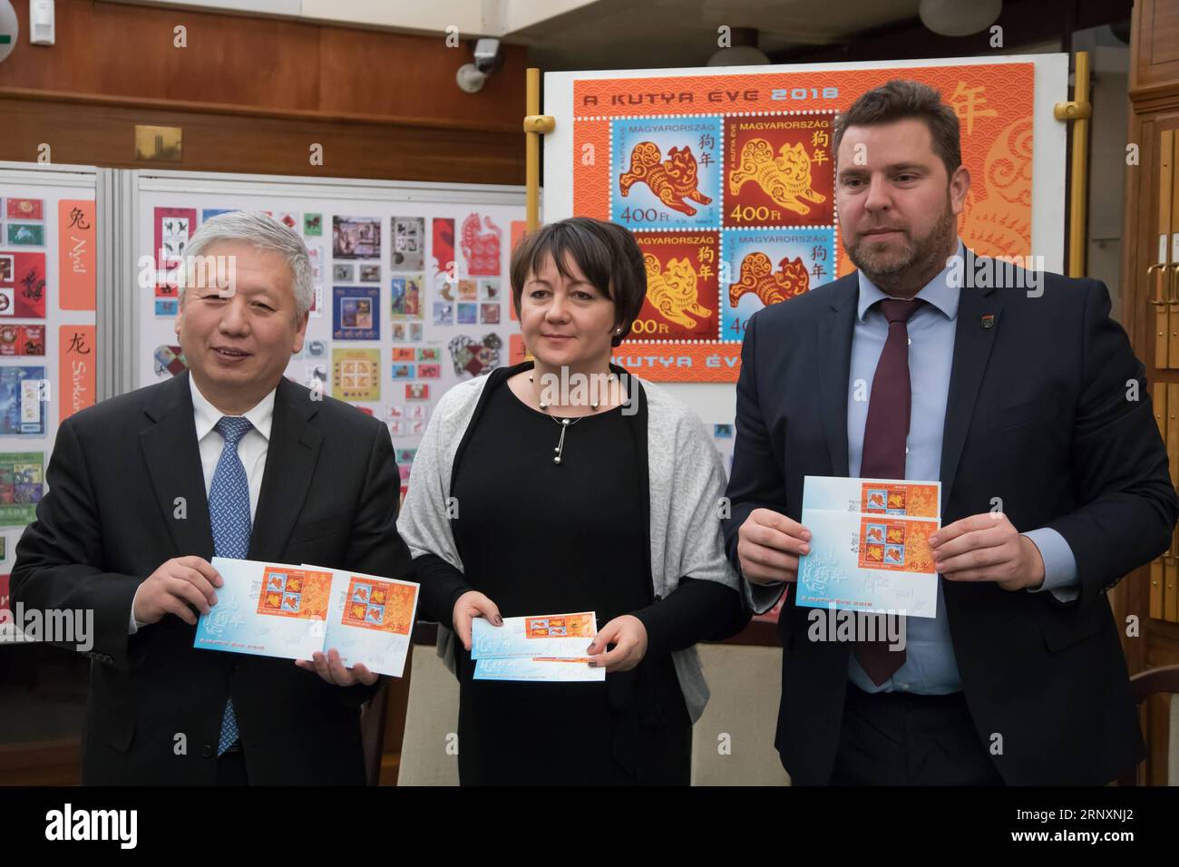 (180207) -- BUDAPEST, 7 février 2018 -- l'ambassadeur de Chine en Hongrie Duan Jielong (G), Juhasz Edit (C), secrétaire d'État adjoint au ministère du développement national de la Hongrie, et Zoltan Illes, président-directeur général de la poste hongroise, posent pour une photo avec les couvertures du premier jour qu'ils ont dédicacées au Musée hongrois du timbre à Budapest, Hongrie, le 6 février 2018. Le timbre spécial du zodiaque émis par la poste hongroise en l'honneur de l'année chinoise du chien a été présenté au public mardi au musée hongrois du timbre. Il s'agit de la cinquième édition d'un timbre hongrois commémorant le Banque D'Images