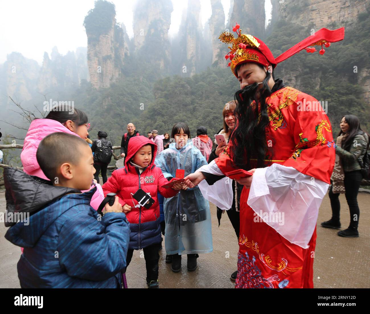 (180220) -- ZHANG JIAJIE, 20 février 2018 -- un homme habillé en Dieu de la richesse distribue des paquets rouges chanceux à des enfants au lieu pittoresque de Wulinyuan à Zhangjiajie, dans la province du Hunan du centre de la Chine, le 20 février 2018, le cinquième jour du nouvel an lunaire chinois qui est censé être l'anniversaire du Dieu de la richesse. Le Dieu de la richesse est censé apporter la fortune aux gens. ) (Wyo) CHINE-LUNAR NOUVEL AN-DIEU DE LA RICHESSE (CN) WuxYongbing PUBLICATIONxNOTxINxCHN Banque D'Images