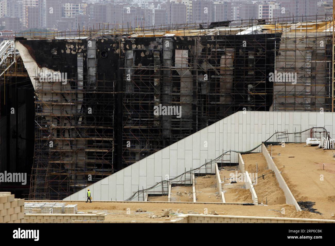 (180505) -- LE CAIRE, 5 mai 2018 -- un constructeur égyptien passe devant l'échafaudage du Grand Musée égyptien (GEM) en construction, qui était en feu dimanche dernier, à Gizeh, en Égypte, le 5 mai 2018. Le GEM, situé sur le plateau de Gizeh, devrait être ouvert plus tard cette année, avec 70 pour cent de sa construction déjà terminée, a déclaré le ministre égyptien des Antiquités Khaled Anany. (Zjl) ÉGYPTE-GIZA-GRAND MUSÉE ÉGYPTIEN-CONSTRUCTION AhmedxGomaa PUBLICATIONxNOTxINxCHN Banque D'Images