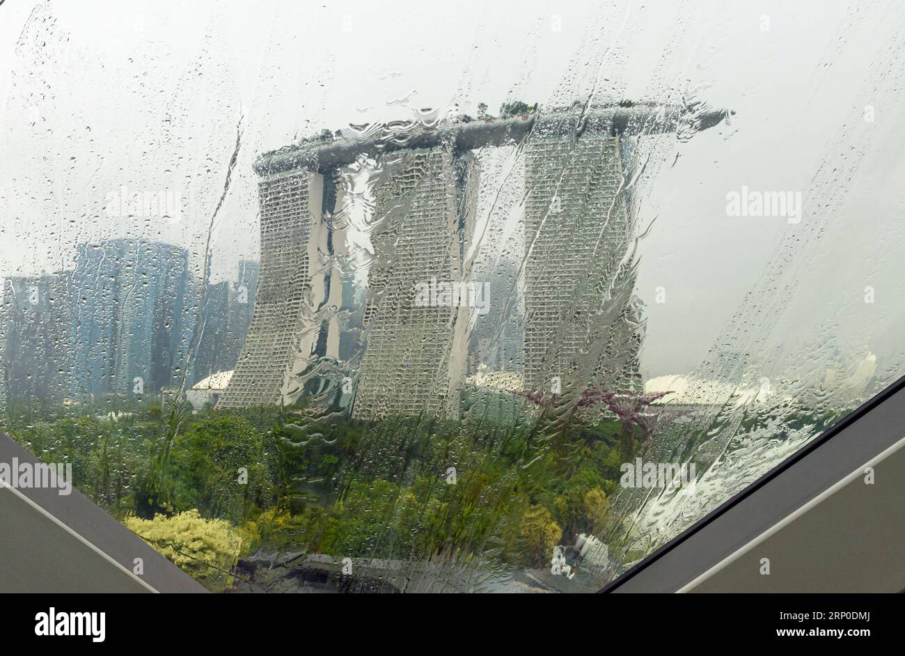Vues tropicales pluvieuses à travers les fenêtres en verre qui donnent sur l'emblématique Marina Bay Sands Hotel de Singapour Banque D'Images