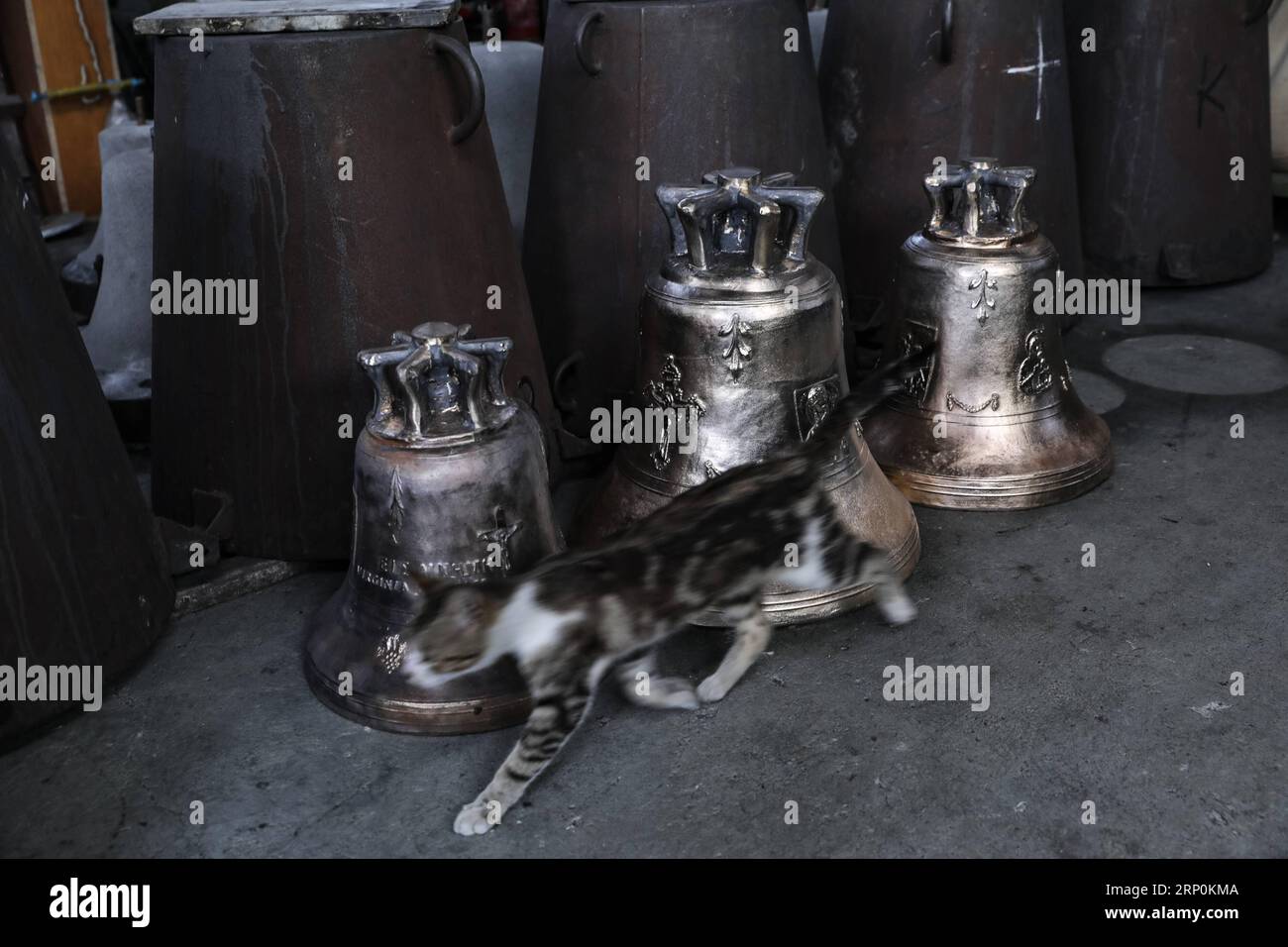 (180518) -- CHANIA, 18 mai 2018 -- Un chat passe devant les cloches de l'usine Stratos Papadoulakis à Chania, Crète, Grèce, le 16 mai 2018. Stratos Papadoulakis travaille dans cette fonderie de cloches depuis l'âge de 12 ans. GRÈCE-CHANIA-BELL FONDERIE LefterisxPartsalis PUBLICATIONxNOTxINxCHN Banque D'Images