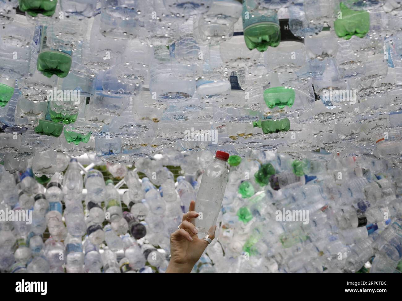 (180524) -- LONDRES, 24 mai 2018 -- Une personne pose pour une photo ajoutant une bouteille en plastique à l'œuvre The Space of Waste, une installation artistique mettant en évidence le problème de la pollution plastique, au Zoo de Londres ZSL à Londres, en Grande-Bretagne, le 24 mai 2018. L'œuvre, de l'artiste et architecte Nick Wood, mesure 16 pieds de haut et est faite à partir de 15 000 bouteilles en plastique à usage unique jetées collectées à Londres et ses rivières. (lrz) BRITAIN-LONDON-PLASTIC ART TimxIreland PUBLICATIONxNOTxINxCHN Banque D'Images