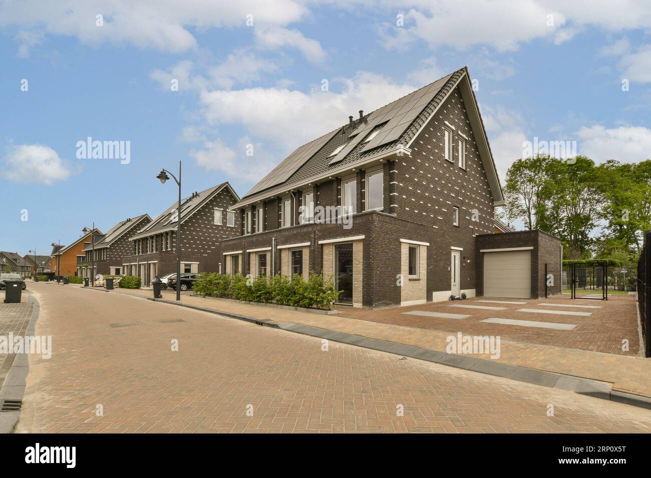 une rue avec des maisons en arrière-plan et des gens marchant sur le trottoir pour obtenir des informations sur ce qu'ils font Banque D'Images