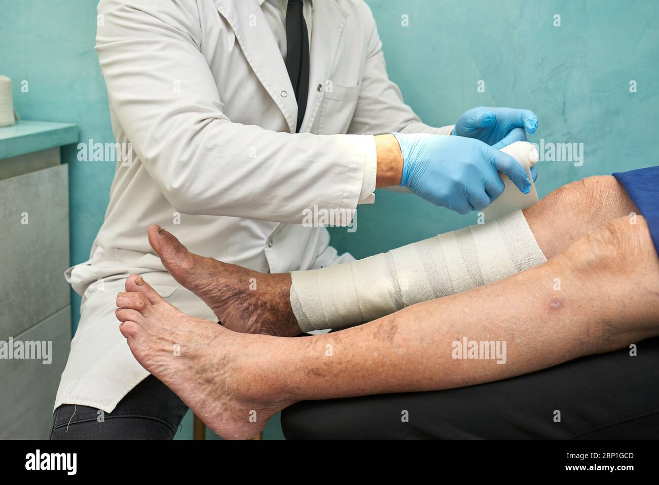Docteur enveloppant des bandages de compression autour des jambes d'une femme Banque D'Images