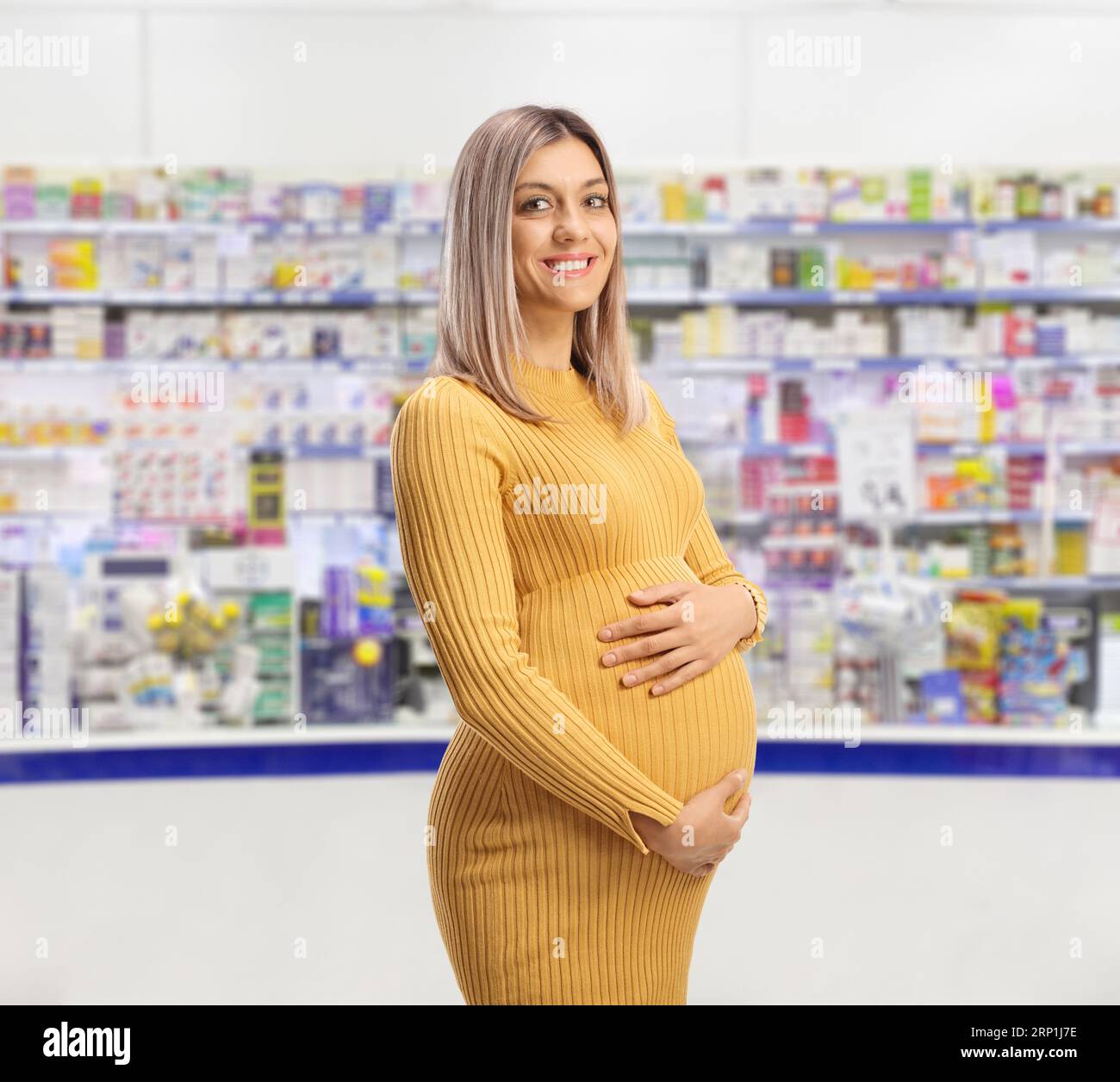 Femme enceinte tenant son ventre et posant à l'intérieur d'une pharmacie Banque D'Images