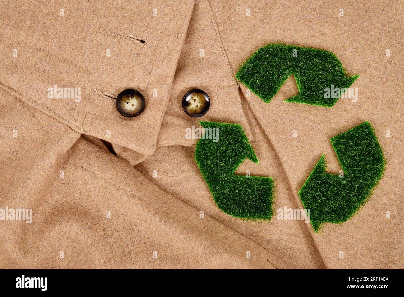Symbole de flèche de recyclage en herbe sur manteau beige. Concept pour vêtements produits respectueux de l'environnement Banque D'Images