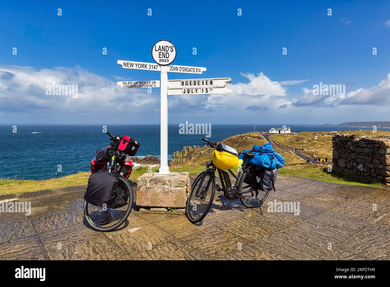 Deux e-bikes au célèbre panneau indiquant New York, John o' Groats et les îles Scilly, LANd's End, Lands End, Penzance, Peninsula Penwith, Cornwall Banque D'Images