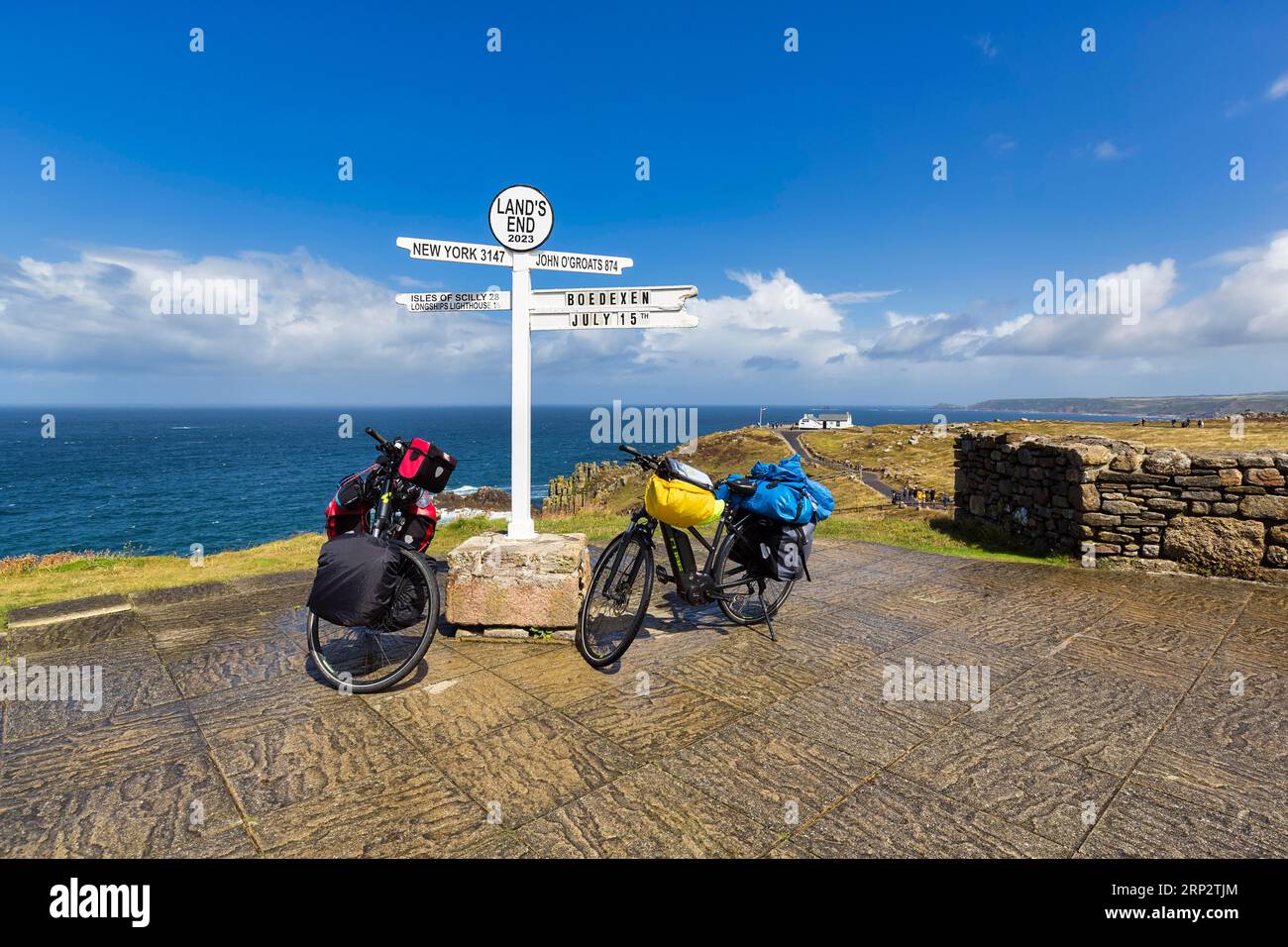 Deux e-bikes au célèbre panneau indiquant New York, John o' Groats et les îles Scilly, LANd's End, Lands End, Penzance, Penwith Peninsula, Cornwall Banque D'Images