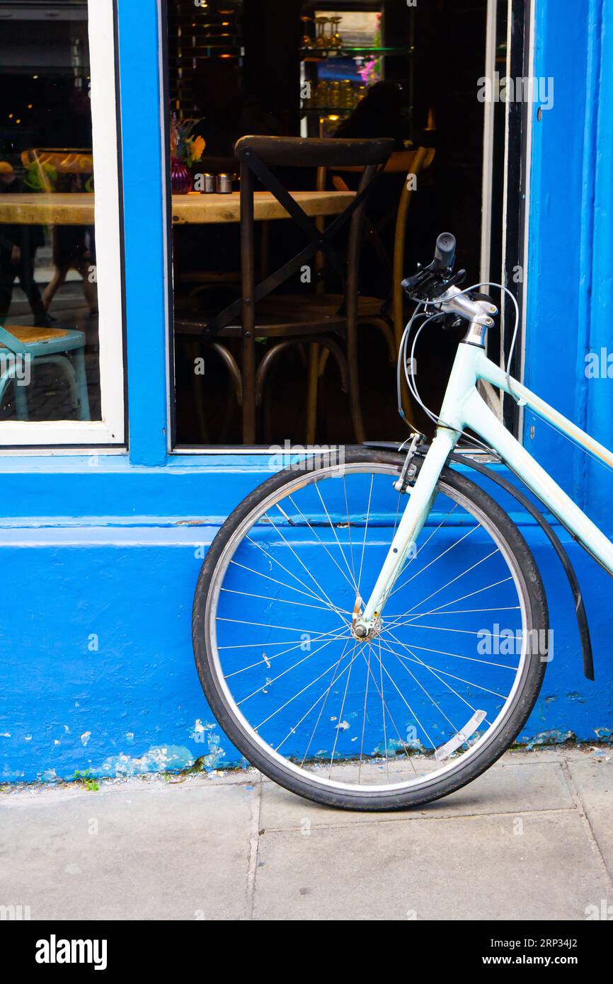 Vélo bleu clair appuyé contre un mur bleu à Édimbourg. Prise de vue verticale. Banque D'Images