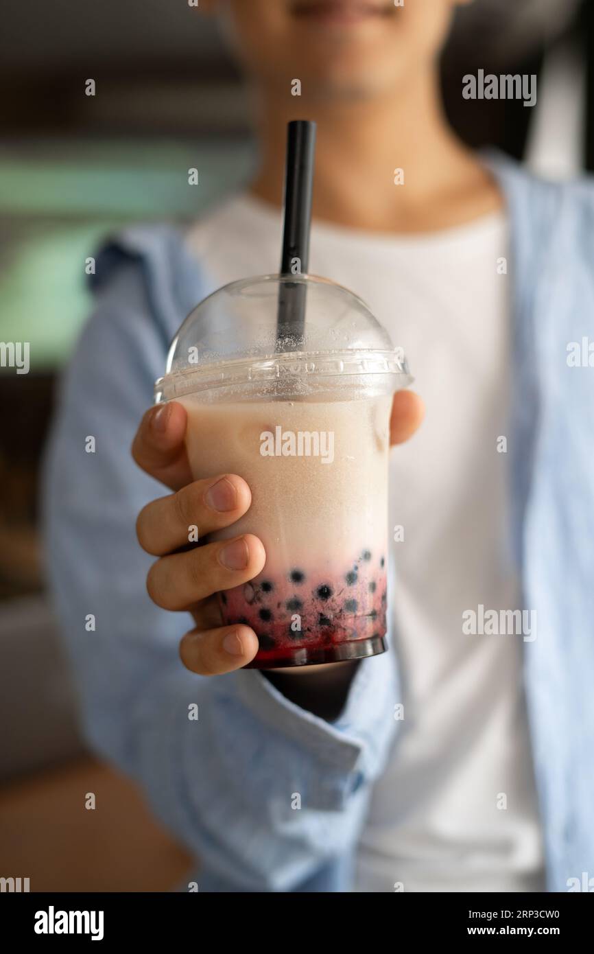 Homme main tenant le thé bulle de lait glacé avec des perles de tapioca et le montre à la caméra, boisson traditionnelle de Taiwan Banque D'Images