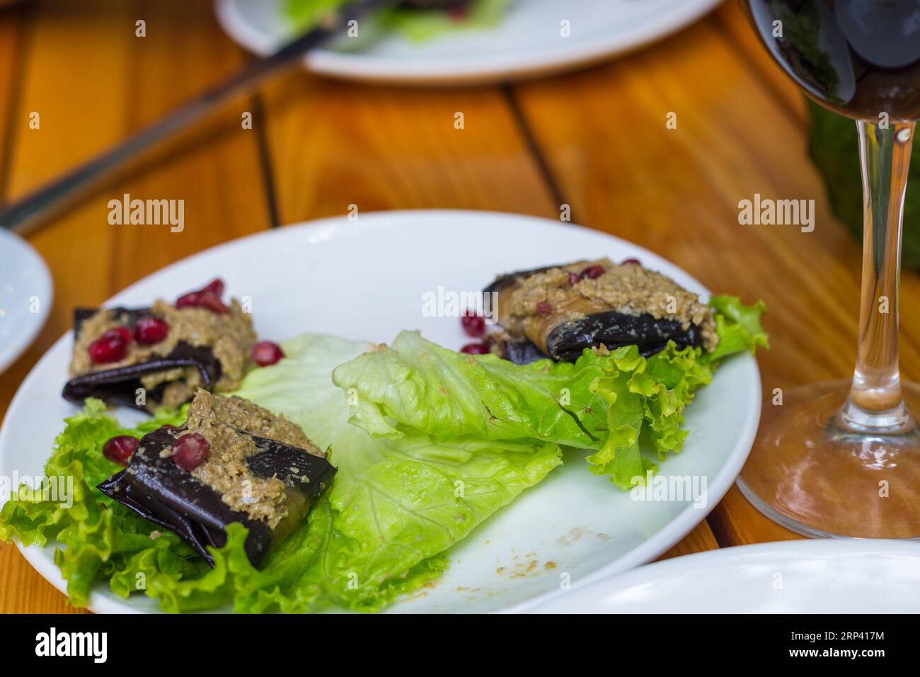 Roulade d'aubergines farcie de noix et de grenade à l'ail et aux épices géorgiennes, servie sur laitue. Banque D'Images