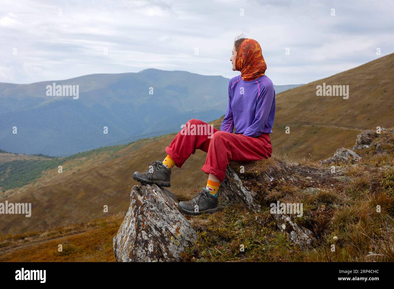 Fille touriste s'assoit et regarde le paysage de montagne Banque D'Images