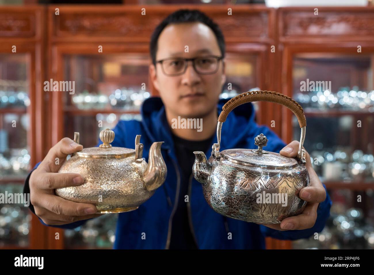 (181110) -- DALI, 10 nov. 2018 (Xinhua) -- un propriétaire d'un magasin d'argenterie compare une bouilloire originale avec un produit sur mesure dans le village de Xinhua du comté de Heqing, préfecture autonome de Dali Bai, province du Yunnan au sud-ouest de la Chine, 8 novembre 2018. Le village, célèbre pour sa tradition de l'argent et de l'orfèvre qui a une histoire de plus de 1 000 ans, est maintenant populaire dans l'ère du magasinage en ligne avec sa valeur de vente annuelle de cuivre et d'articles de mèche à 80 millions de yuans (environ 11 millions de dollars américains). (Xinhua/Hu Chao) (clq) CHINE-YUNNAN-DALI-ARTISANAT-ÉCONOMIE (CN) PUBLICATIONxNOTxINxCHN Banque D'Images