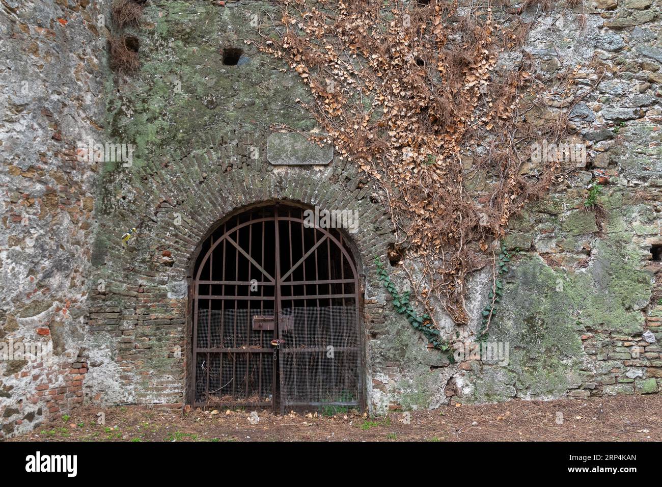 Entrée voûtée fermée par une porte métallique rouillée à l'intérieur de la forteresse de Priamar, construite en 1542 par la République de Gênes, Savone, Ligurie, Italie Banque D'Images