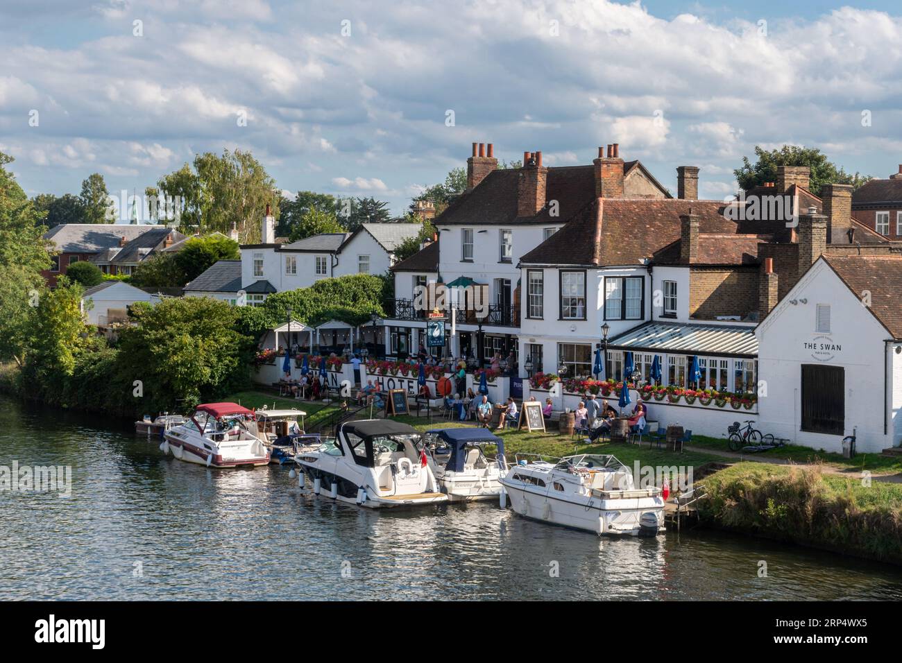 The Swan Hotel, un pub au bord de la Tamise à Staines-upon-Thames, Surrey, Angleterre, Royaume-Uni, avec des bateaux amarrés et des gens dehors prenant un verre Banque D'Images