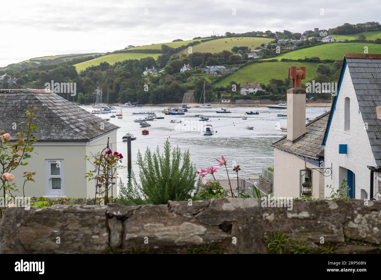 Vue sur les collines de East Portlemouth prise de Buckley Street à Salcombe, avec des bateaux amarrés sur les eaux calmes estivales du port. Banque D'Images