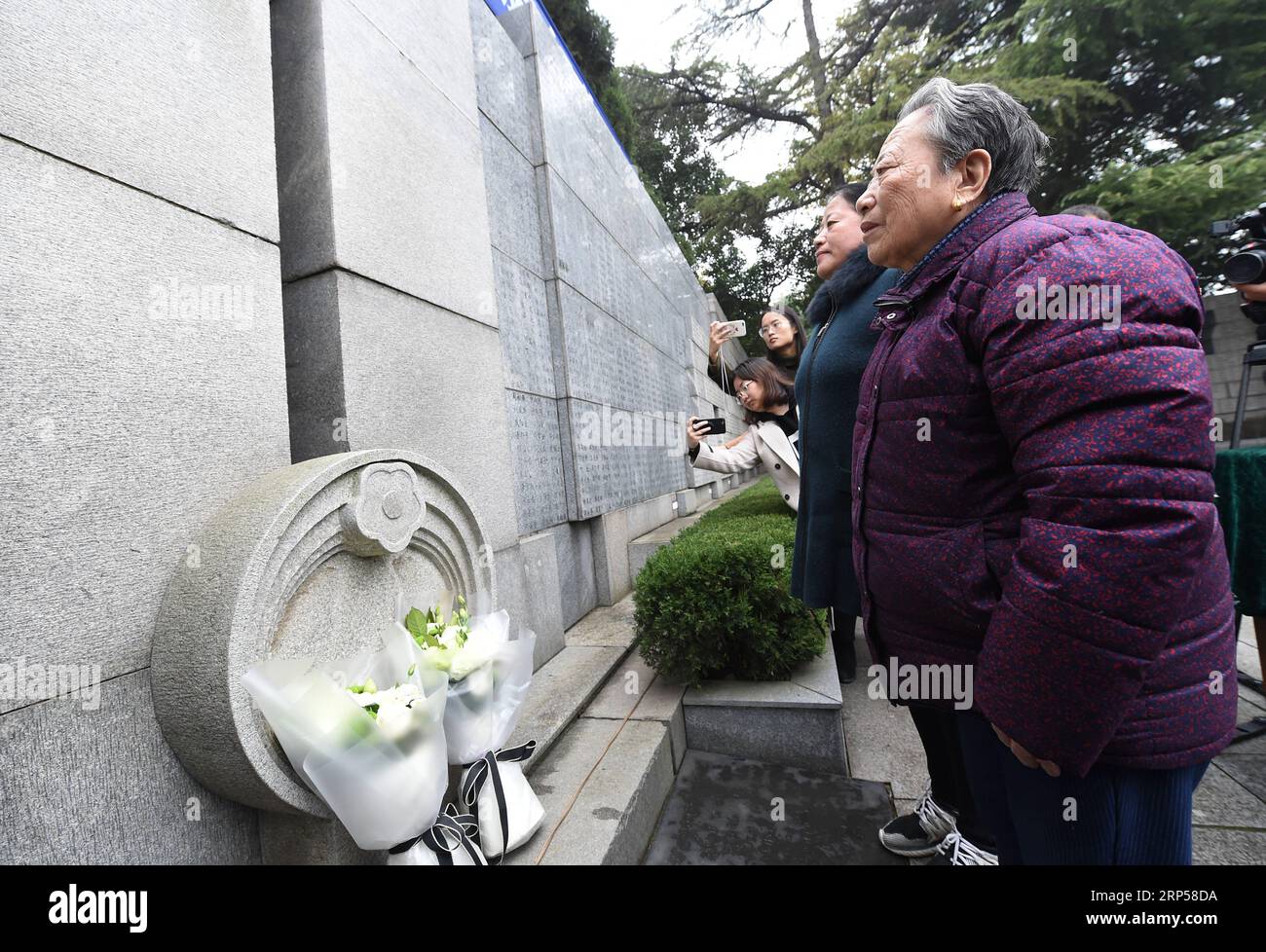 (181203) -- NANJING, 3 déc. 2018 (Xinhua) -- le survivant du massacre de Nanjing Shi Xiuying, 92 ans, rend hommage aux victimes du massacre de Nanjing devant le mur de la salle commémorative où les noms des victimes sont gravés lors des activités de commémoration à Nanjing, capitale de la province de Jiangsu de l est de la Chine, le 3 décembre 2018. Le massacre de Nankin a eu lieu lorsque les troupes japonaises ont capturé la ville le 13 décembre 1937. En six semaines, ils ont tué 300 000 civils chinois et des soldats non armés. En février 2014, la plus haute législature de la Chine a désigné le 13 décembre comme jour commémoratif national pour les victimes de Nanjing Banque D'Images