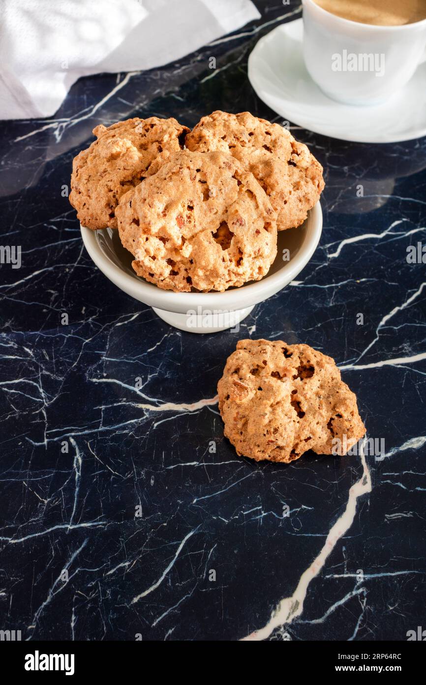 Biscuits aux amandes faits maison avec une tasse blanche de latte sur un fond de marbre bleu marine avec des lignes blanches. arrière-plan vertical Banque D'Images