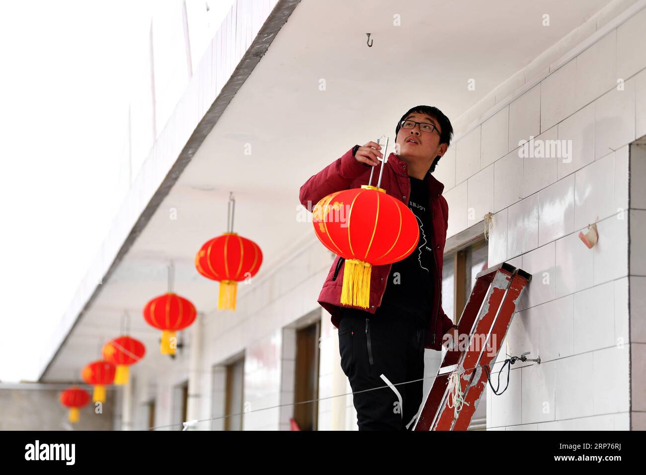 (190129) -- COMTÉ DE WENXI, 29 janvier 2019 (Xinhua) -- un résident de la colonie de lutte contre la pauvreté Home of Happiness accroche des lanternes rouges pour le festival du printemps à venir dans le village de Zhangcailing, dans le canton de Yangyu, comté de Wenxi, province du Shanxi au nord de la Chine, le 27 janvier 2019. Pendant des générations, les habitants du village de Zhangcailing ont à peine arraché leur vie en raison de leur isolement géographique, de la médiocrité des infrastructures et du manque d’industries de soutien. Pour aider les villageois à sortir de la pauvreté, le gouvernement a augmenté son soutien financier en encourageant l'agriculture et l'élevage adaptés aux conditions locales. Banque D'Images