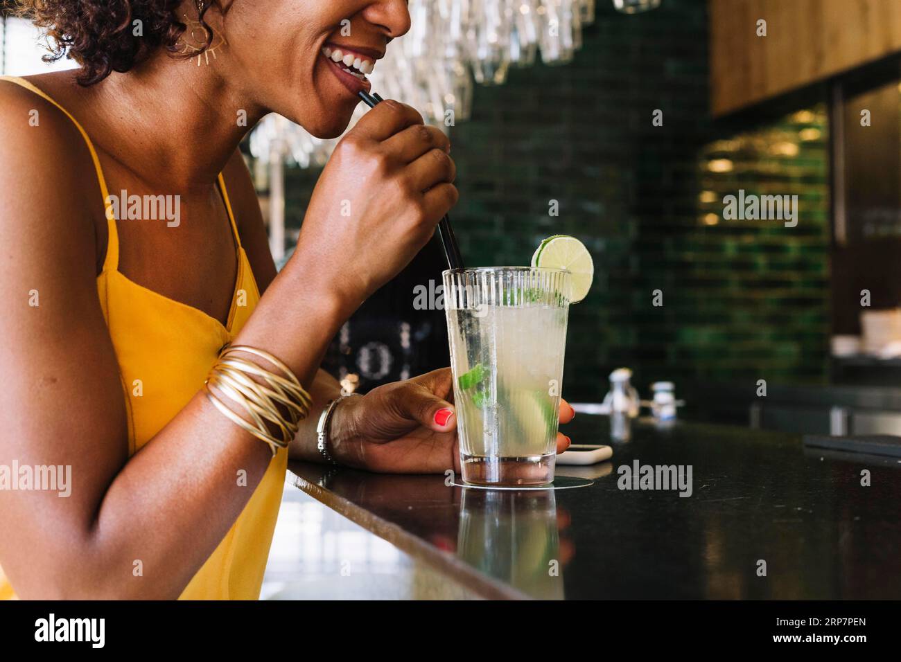 Une jeune femme souriante boit au bar-restaurant Mojito Banque D'Images