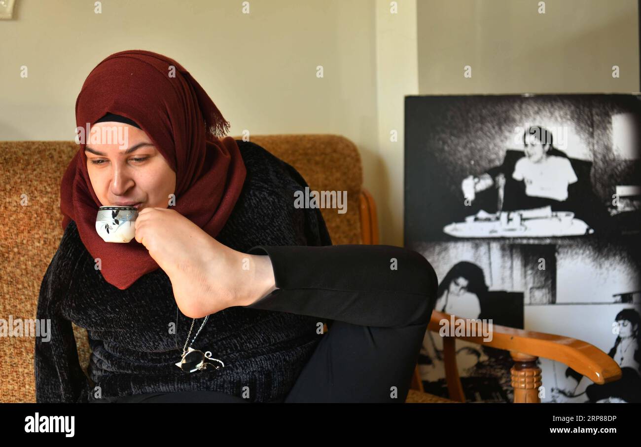 (190221) -- DAMAS, 21 février 2019 -- Dua al-Busti, 28 ans, boit du café avec son pied dans sa maison de la banlieue de Sehnaya, dans la campagne de Damas, capitale de la Syrie, le 20 février 2019. Dua al-Busti est né sans armes. Cependant, elle est devenue capable de briser les limites avec son talent de dessiner diverses peintures avec ses pieds.) SYRIE-DAMAS-ARTISTE SANS BRAS AmmarxSafarjalani PUBLICATIONxNOTxINxCHN Banque D'Images