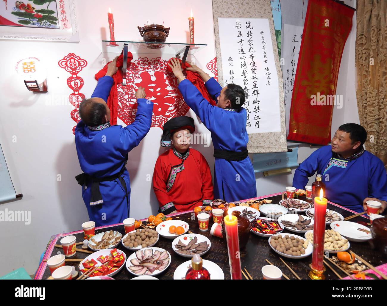 (190227) -- XINGWEN, 27 février 2019 (Xinhua) -- des membres de la famille pendent un tissu rouge devant le sanctuaire familial dans le comté de Xingwen, dans la province du Sichuan du sud-ouest de la Chine, le 25 février 2019. Yang Yuqiao et Han Yujie, un couple ethnique Miao, ont noué le nœud dans le style traditionnel Miao dans le comté de Wenxing, dans la province du Sichuan du sud-ouest de la Chine, du 24 au 26 février 2019. Yang Yuqiao, le marié de 25 ans, travaille comme guide touristique dans le Géoparc mondial UNESCO de Xingwen, et Han Yujie, la mariée de 23 ans, travaille comme professeur d'éducation physique dans le canton de Dahe Miao dans le comté de Xingwen. Pendant le travail bénévole du Festival Huashan pour la Mia Banque D'Images