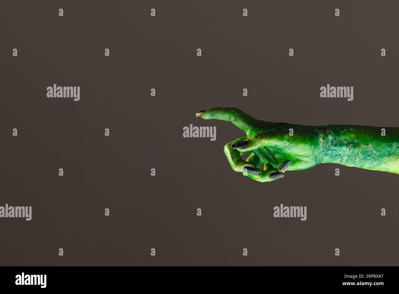 Main de monstre vert avec des ongles noirs pointant avec le doigt sur fond gris Banque D'Images