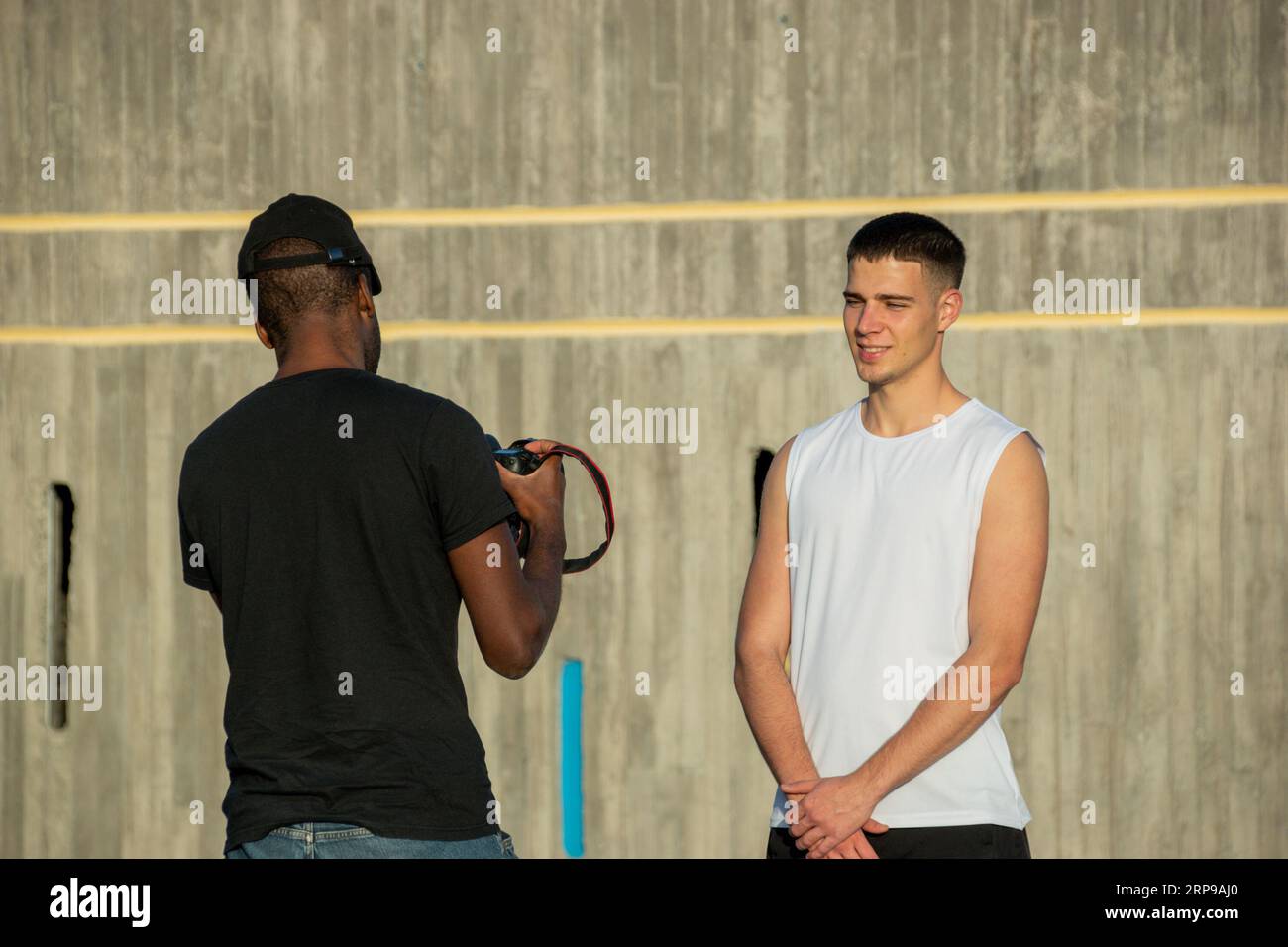 Photographe professionnel afro-américain prend des photos d'un jeune joueur de basket caucasien Banque D'Images