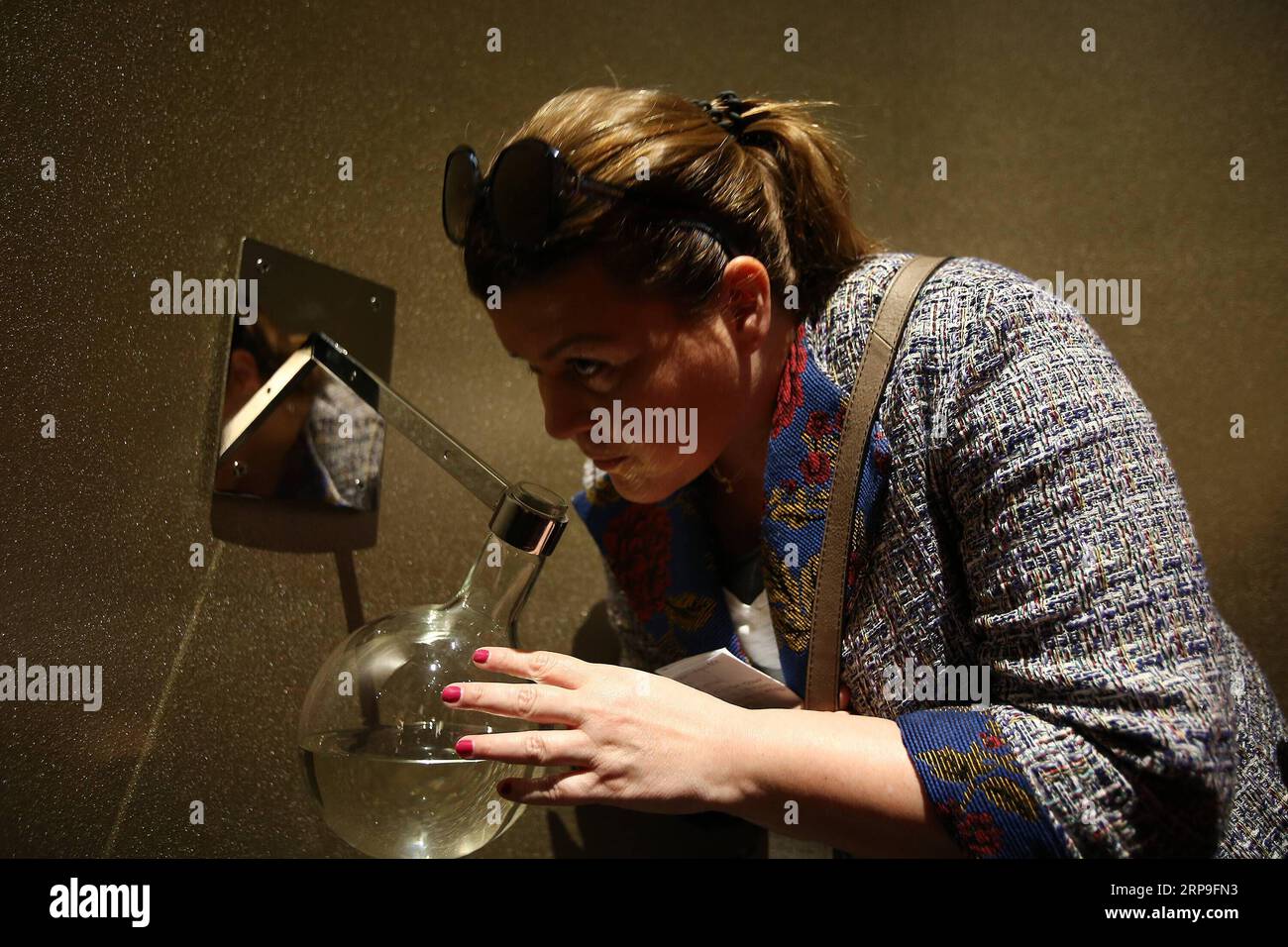 (190405) -- ATHÈNES, 5 avril 2019 -- un visiteur sent l'un des deux parfums qui accompagnent une statue romaine de la déesse grecque Aphrodite, qui est exposée pour la première fois à l'exposition les innombrables aspects de la beauté organisée par le Musée archéologique national, à Athènes, Grèce, le 4 avril 2019. Une statue en marbre de la déesse grecque antique Aphrodite ainsi que deux parfums de l'antiquité ont été dévoilés jeudi au Musée archéologique national de Grèce pour marquer le premier anniversaire de l'exposition temporaire les innombrables aspects de la beauté. POUR ALLER AVEC caractéristique : statue d'Aphrodite sur ma Banque D'Images