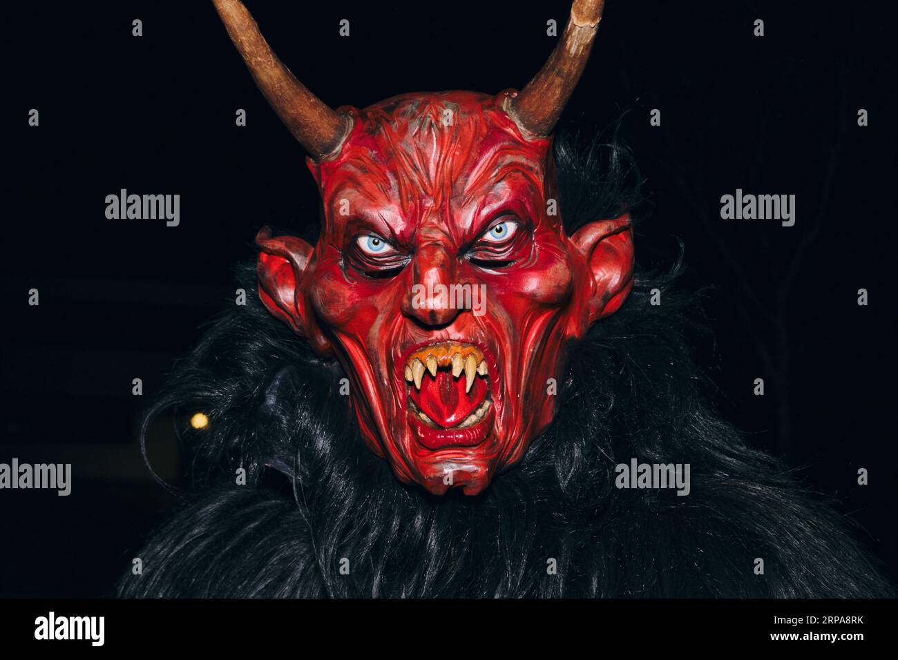 Une vue rapprochée d'une personne en costume de diable, debout devant une toile de fond de studio tout en posant pour une photographie Banque D'Images