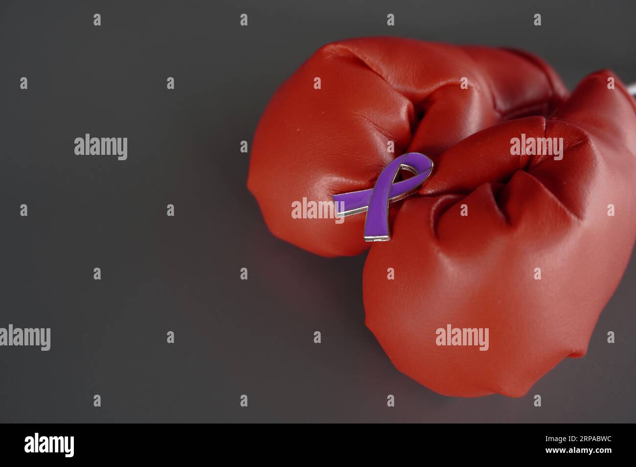 Image rapprochée de gants de boxe et ruban violet avec espace de copie. Cancer du pancréas, épilepsie et concept de sensibilisation à la maladie d'Alzheimer Banque D'Images