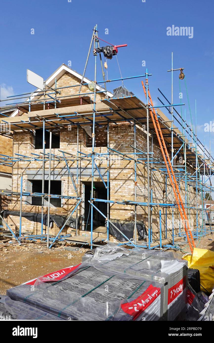 Palan électrique en position sur l'échafaudage pour soulever Marley tuiles béton brique extrémité pignon terminé sur la nouvelle construction propriété résidentielle détachée Angleterre Royaume-Uni Banque D'Images