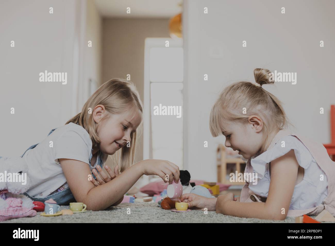 Gros plan d'enfants de sexe féminin jouant avec un ensemble de thé de jeu de jouet coloré. Enfants couchés à la maison chambre ou maternelle, crèche. Jeu écologique éducatif pour enfant. Développement de la pensée logique Banque D'Images
