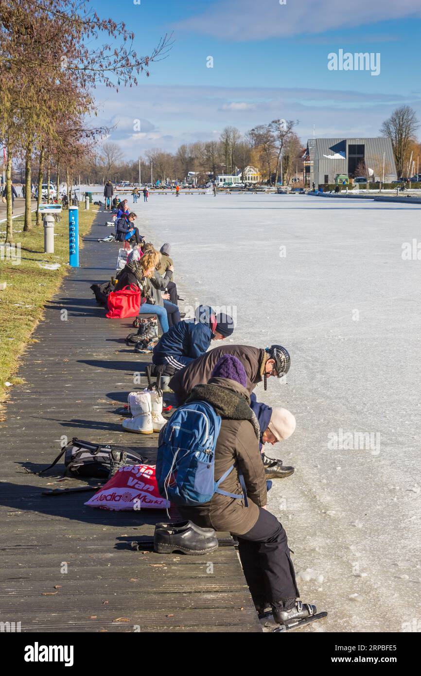 Des gens qui mettent leurs patins au bord du lac à Paterswolde, pays-Bas Banque D'Images