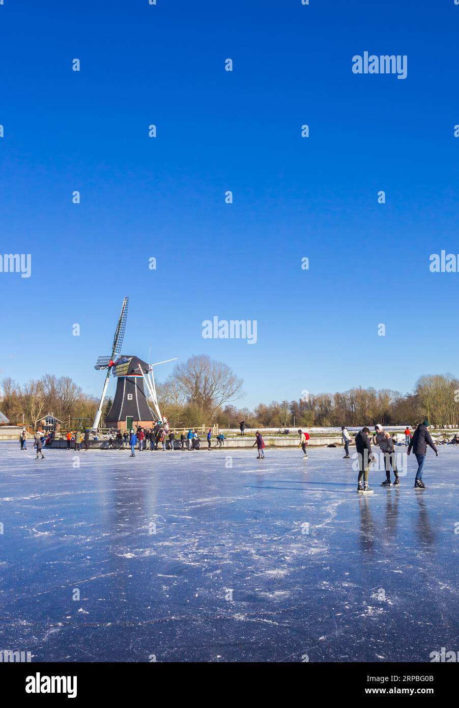 Patineurs devant le moulin à vent au lac gelé de Groningen, pays-Bas Banque D'Images