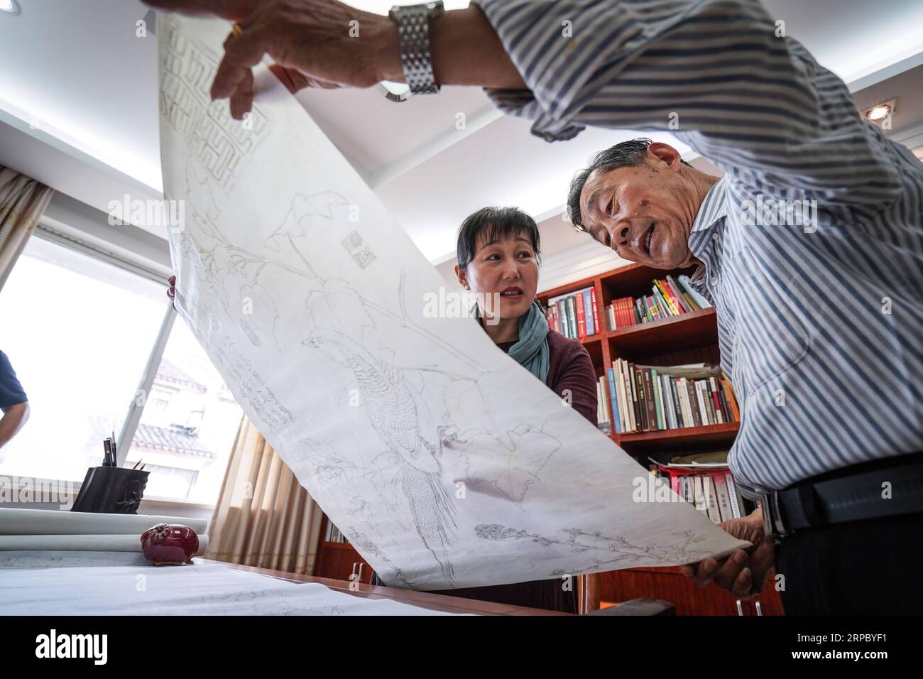 (190619) -- NANJING, 19 juin 2019 (Xinhua) -- Yao Huifen (à gauche) et son père échangent sur une peinture dans son atelier de Zhenhu, ville de Suzhou, province du Jiangsu dans l'est de la Chine, 29 mai 2019. Suzhou broderie, l'une des quatre broderies les plus célèbres en Chine, est originaire de Suzhou et a une histoire de plus de 2 000 ans. Connu pour son motif élégant, son design artistique, son travail manuel fin et ses coutures variées, il a été inscrit au patrimoine culturel immatériel national de la Chine en 2006. Yao Huifen, héritier représentatif de l’artisanat, est né à Suzhou en 1967 dans une famille de broderies. Influencé b Banque D'Images