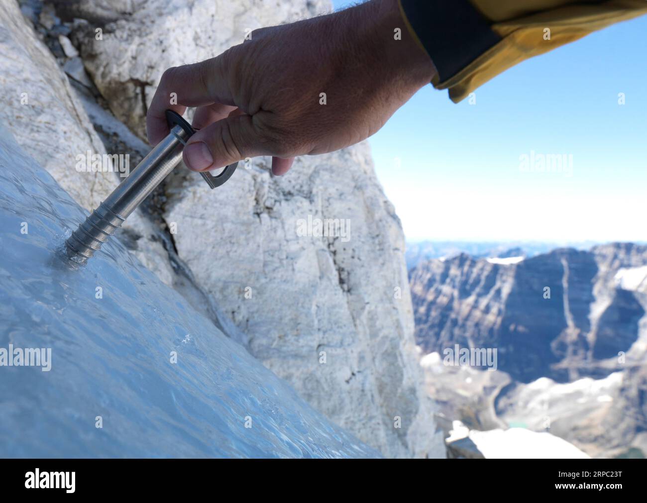 POV des mains du grimpeur fixant la vis à glace au-dessus des montagnes Banque D'Images