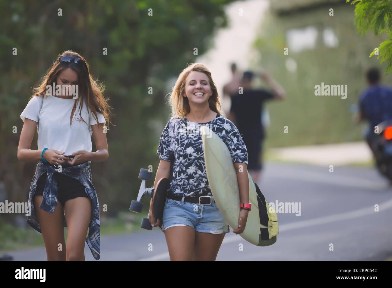 Femme portant skateboard et planche de surf Banque D'Images
