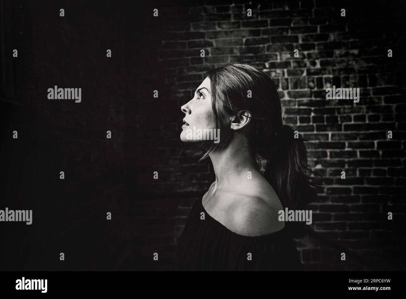 Jeune femme de profil avec des épaules montrant vers le haut regardant la lumière Banque D'Images