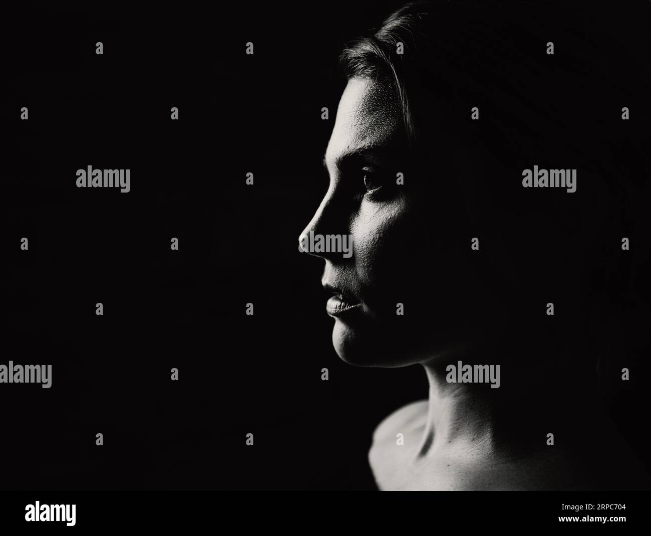 Un gros plan d'une jeune femme de profil dans une lumière dramatique Banque D'Images