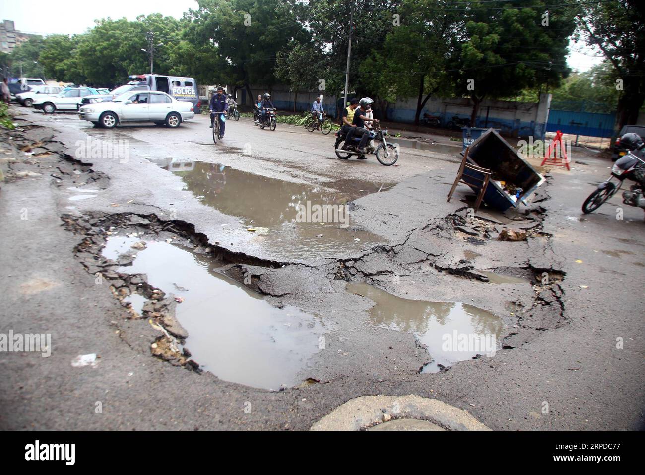 (190730) -- KARACHI, 30 juillet 2019 (Xinhua) -- des gens passent devant une route endommagée après de fortes pluies de mousson dans la ville portuaire de Karachi, dans le sud du Pakistan, le 30 juillet 2019. Au moins 83 personnes ont été tuées et 74 autres blessées dans des accidents séparés liés à la pluie à travers le Pakistan au cours du mois en cours, a déclaré mardi l'Autorité nationale de gestion des catastrophes (NDMA). (Str/Xinhua) PAKISTAN-KARACHI-RAIN PUBLICATIONxNOTxINxCHN Banque D'Images