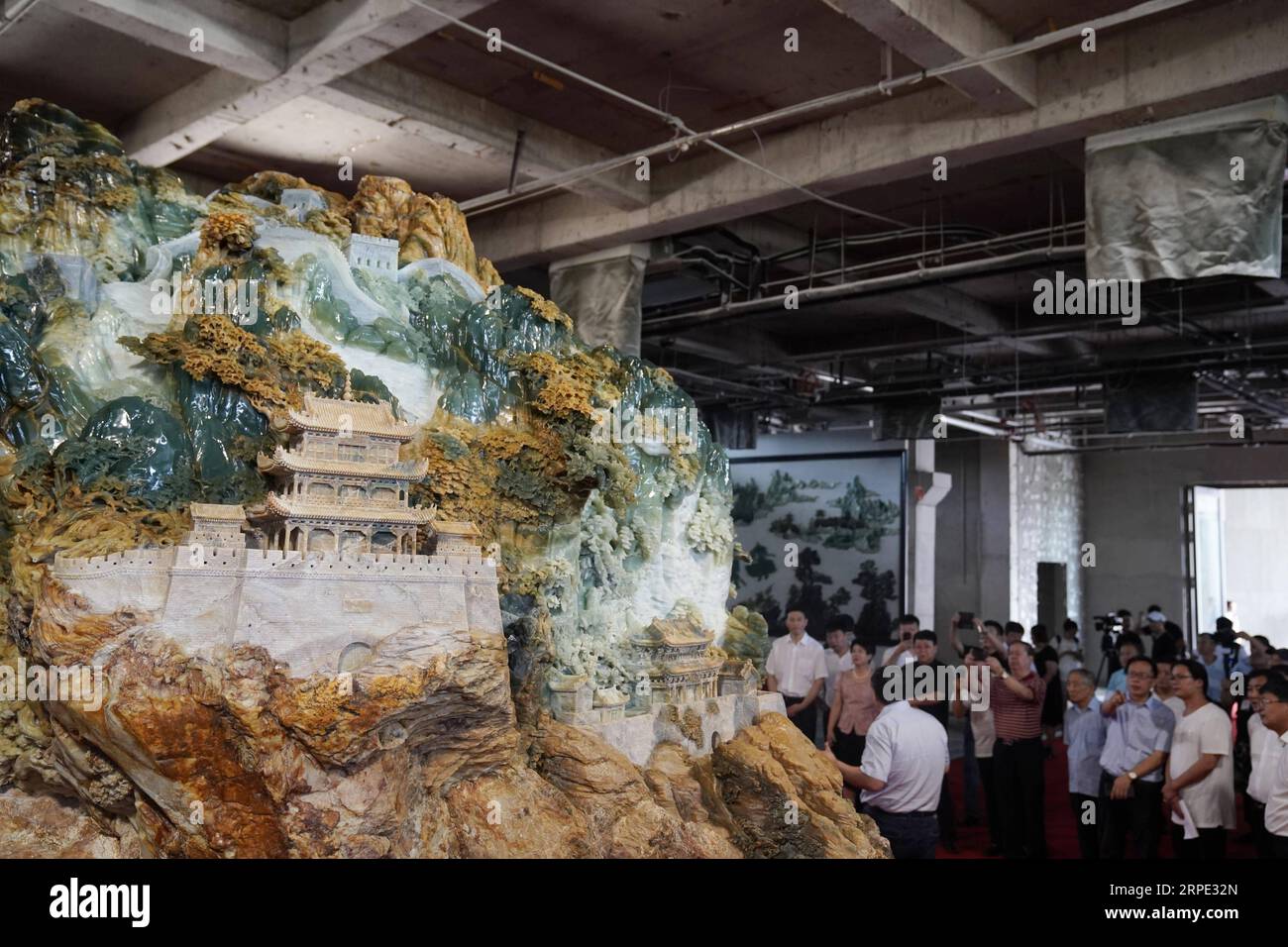 (190816) -- XIUYAN, 16 août 2019 -- les visiteurs voient une œuvre de sculpture en jade géante de la Grande Muraille dans un centre culturel et artistique du comté autonome de Xiuyan Man, province du Liaoning au nord-est de la Chine, 16 août 2019. L'œuvre, d'environ 6,5 mètres de long, 3 mètres de haut et 4 mètres de large, est faite d'un morceau de jade pesant 118 tonnes par plus de 30 sculpteurs pendant 14 mois. CHINA-LIAONING-XIUYAN-JADE SCULPTURE-GRAND MUR (CN) JINXLIANGKUAI PUBLICATIONXNOTXINXCHN Banque D'Images