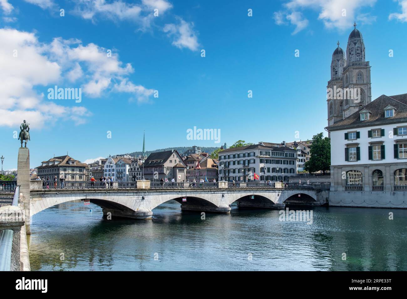 Zurich, Suisse-27 mai 2023 ; Munsterbrucke (pont) au-dessus de la rivière Limmat à Altstadt Zurich avec l'église Grossmünster contre un bleu blanc nuageux Banque D'Images