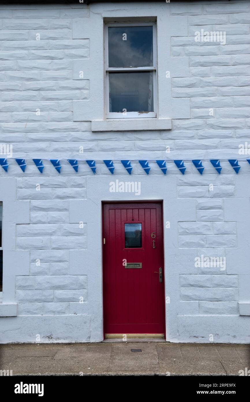 Drapeau écossais le Saltire, la St Andrew’s Cross le drapeau national de l’Écosse suspendu comme un ruban de drapeaux à l’avant d’une maison blanche. Cockenzie et Port Seton, East Lothian, Écosse années 2023 2020 Royaume-Uni HOMER SYKES Banque D'Images