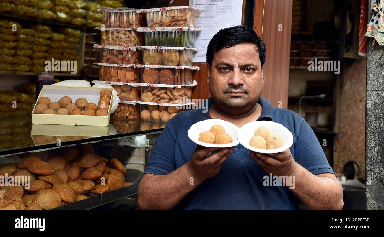 (190827) -- NEW DELHI, 27 août 2019 -- Un vendeur montre des ladoos dans un magasin de desserts traditionnels à New Delhi, en Inde, le 27 août 2019. Ladoo est un bonbon indien généralement fait de farine, de sucre, d'huile végétale, d'épices et de noix. Il y a beaucoup de magasins de desserts vendant des ladoos à travers New Delhi. Les Ladoos sont aimés par les habitants, soit comme collation de thé pour les pauses de l'après-midi, soit comme plat lors de banquets festifs.) INDE-NOUVEAU DELHI-DESSERT-LADOO ZhangxNaijie PUBLICATIONxNOTxINxCHN Banque D'Images