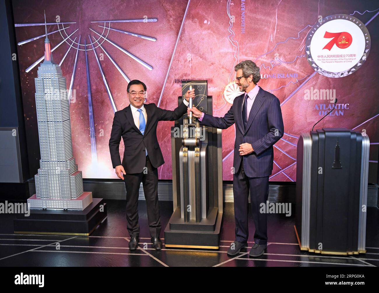 191001 -- NEW YORK, le 1 octobre 2019 -- Consul général de Chine à New York Huang Ping L et Empire State Realty Trust Inc Anthony Malkin, PDG de l'Empire State Building, actionne un interrupteur pour allumer la maquette de l'Empire State Building lors d'une cérémonie d'éclairage à l'Empire State Building à New York, aux États-Unis, le 30 septembre 2019. Le monument historique de New York, l Empire State Building, a été éclairé par un spectacle de lumière lundi soir pour célébrer le 70e anniversaire de la fondation de la République populaire de Chine. L'éclairage de la tour marque également le 40e anniversaire de l'établissement de relations diplomatiques entre les Banque D'Images