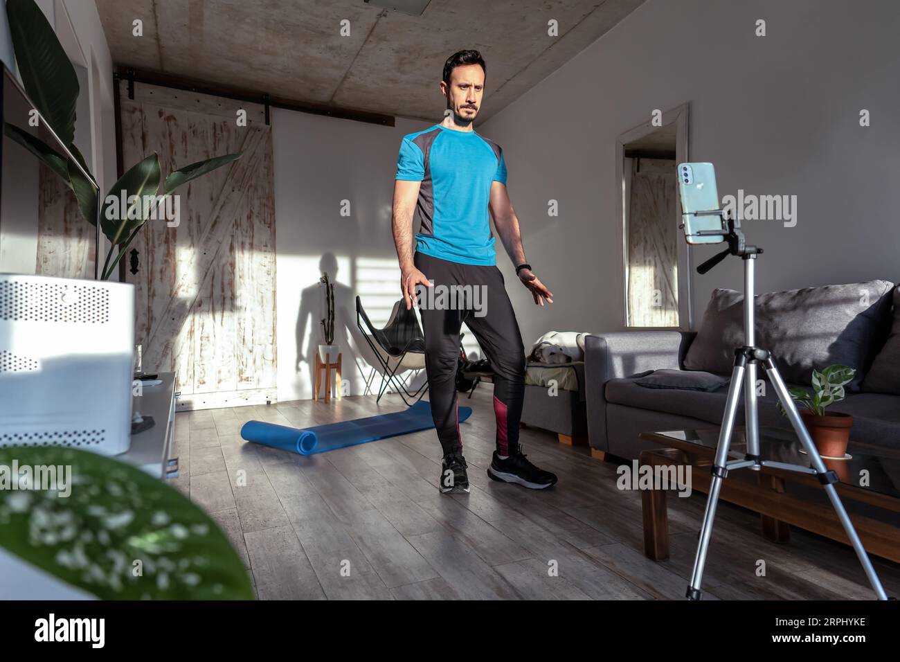 Entraîneur masculin latin streaming entraînement en ligne avec téléphone à la maison. Cours de gym en ligne. Banque D'Images