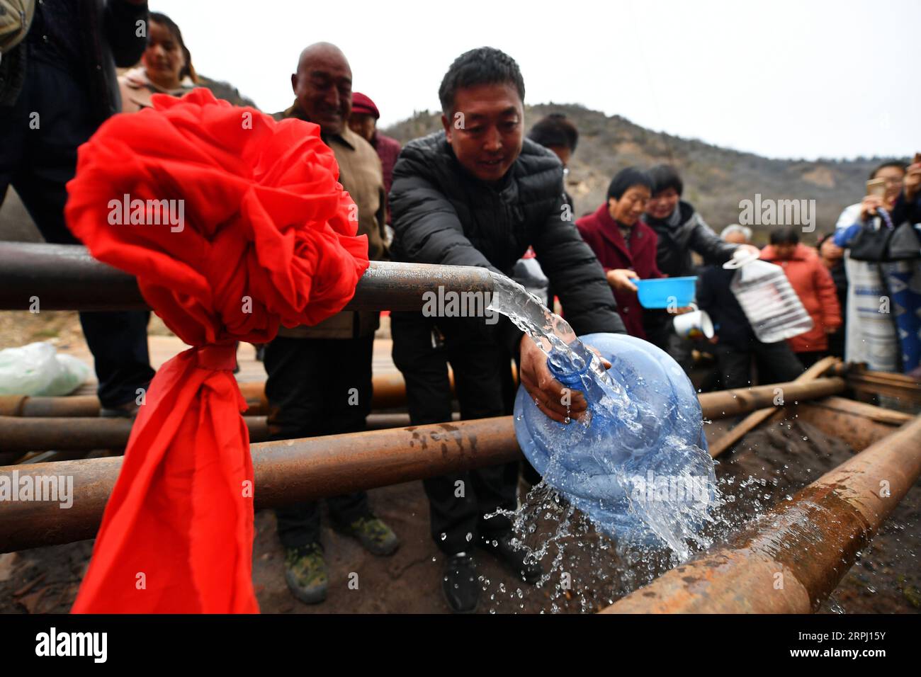 191122 -- COMTÉ DE YICHENG, 22 novembre 2019 -- les villageois se tiennent dans les lignes pour recueillir de l'eau après qu'un puits en eau profonde a commencé à pomper de l'eau souterraine dans le village de Nanling du comté de Yicheng, le 20 novembre 2019. Lorsque l'interrupteur a été tiré, l'eau a jailli de 403 mètres plus bas. Le tout premier puits en eau profonde de Nanling Village a été mis en service un matin tôt d hiver. Dans le passé, le village, qui s’étendait à travers les ravins des montagnes Zhongtiao dans le nord de la Chine, dépendait uniquement des fosses à boue pour stocker sa précieuse eau potable depuis des siècles. Hantées par la peur de la sécheresse, des générations avaient rêvé Banque D'Images
